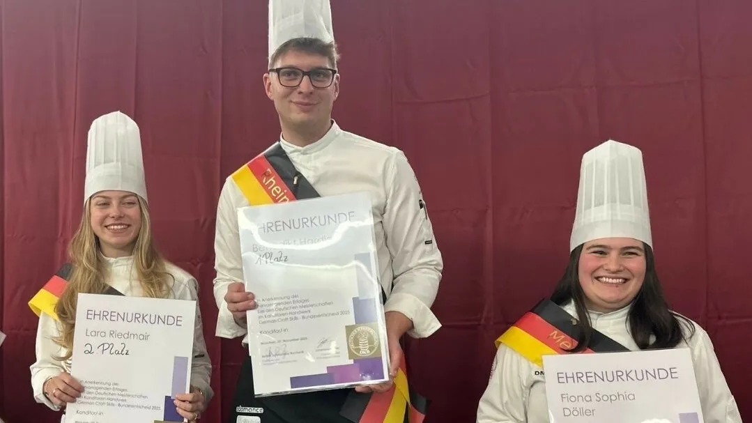 Lara Riedmair, Benedikt Hardieß und Fiona Sophia Döhler (v. l. n. r.) stehen nebeneinander, lächeln und halten ihre Urkunden in die Kamera.